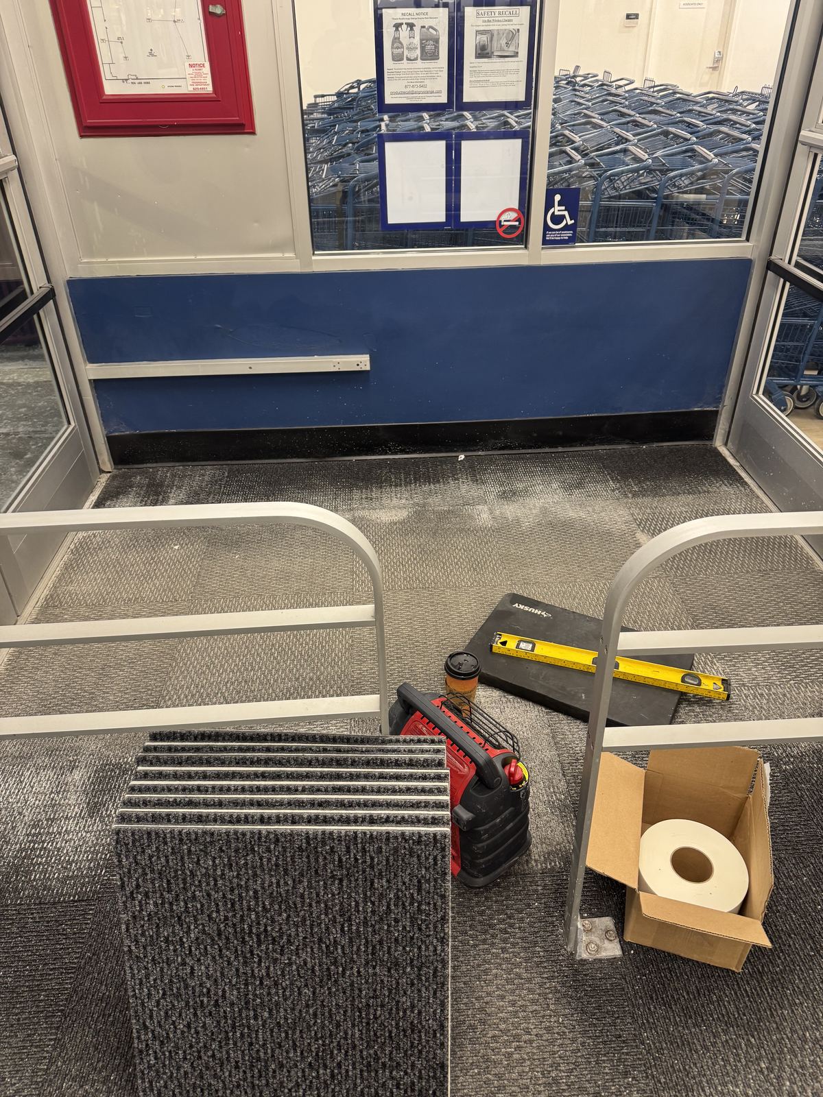 Store entryway during carpet removal, with old flooring and installation tools