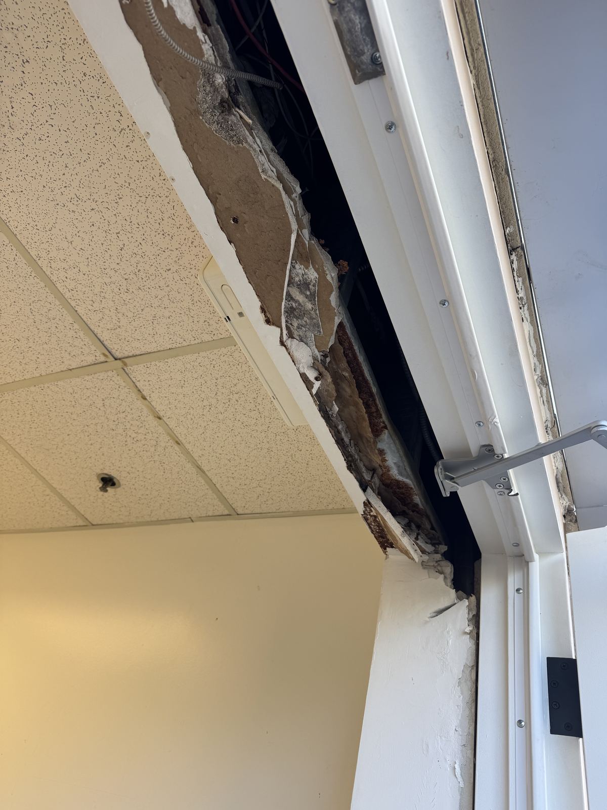 Emergency exit doorway with crumbling plaster and exposed framing above the door